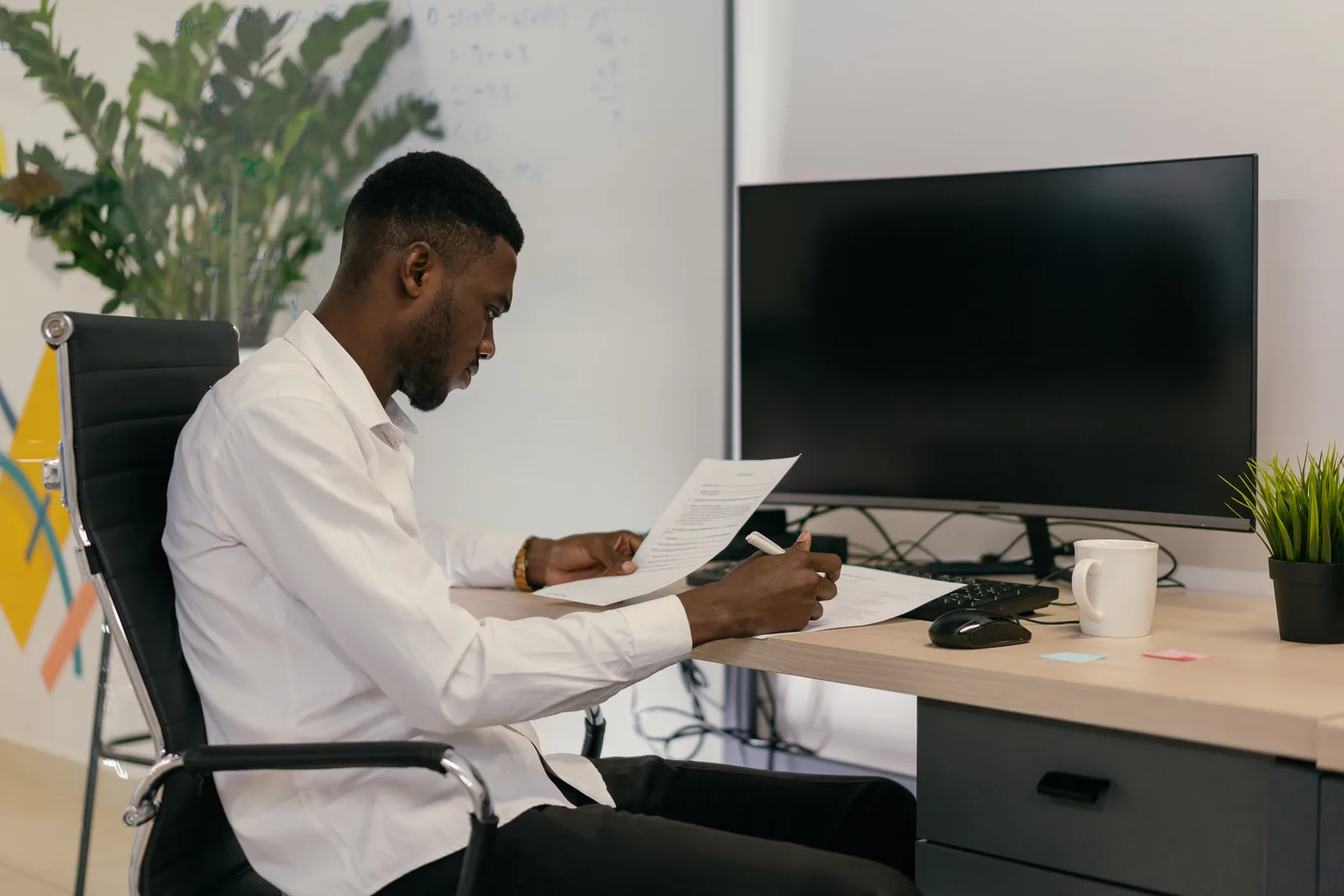 A focused professional working at an office desk with computer and paperwork. Ideal for business concepts.